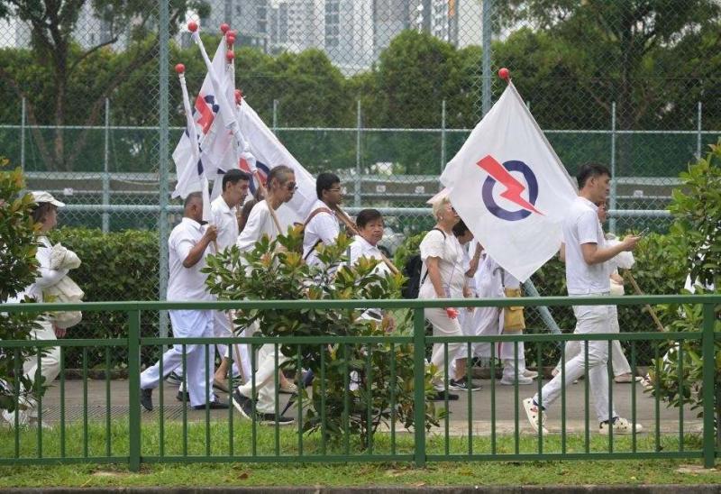 Người ủng hộ Đảng PAP cầm quyền trên đường phố Singapore, ngày 23.4.2025. Ảnh: Xinhua