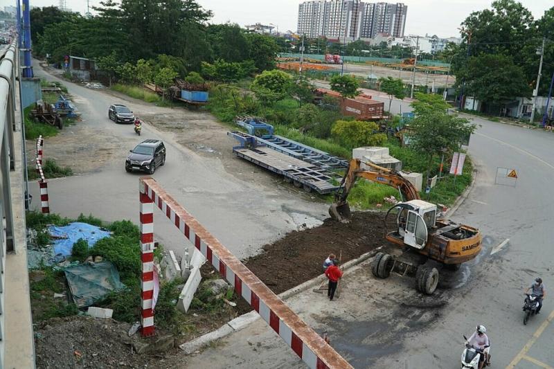 Công nhân thi công gờ phân cách tách phần đường dưới dạ cầu Rạch Chiếc, ngăn xe chạy vòng theo đường bên hông để lên cầu, chiều 30/5. Ảnh: Gia Minh